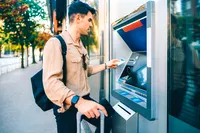 Мужчина пользуется банкоматом